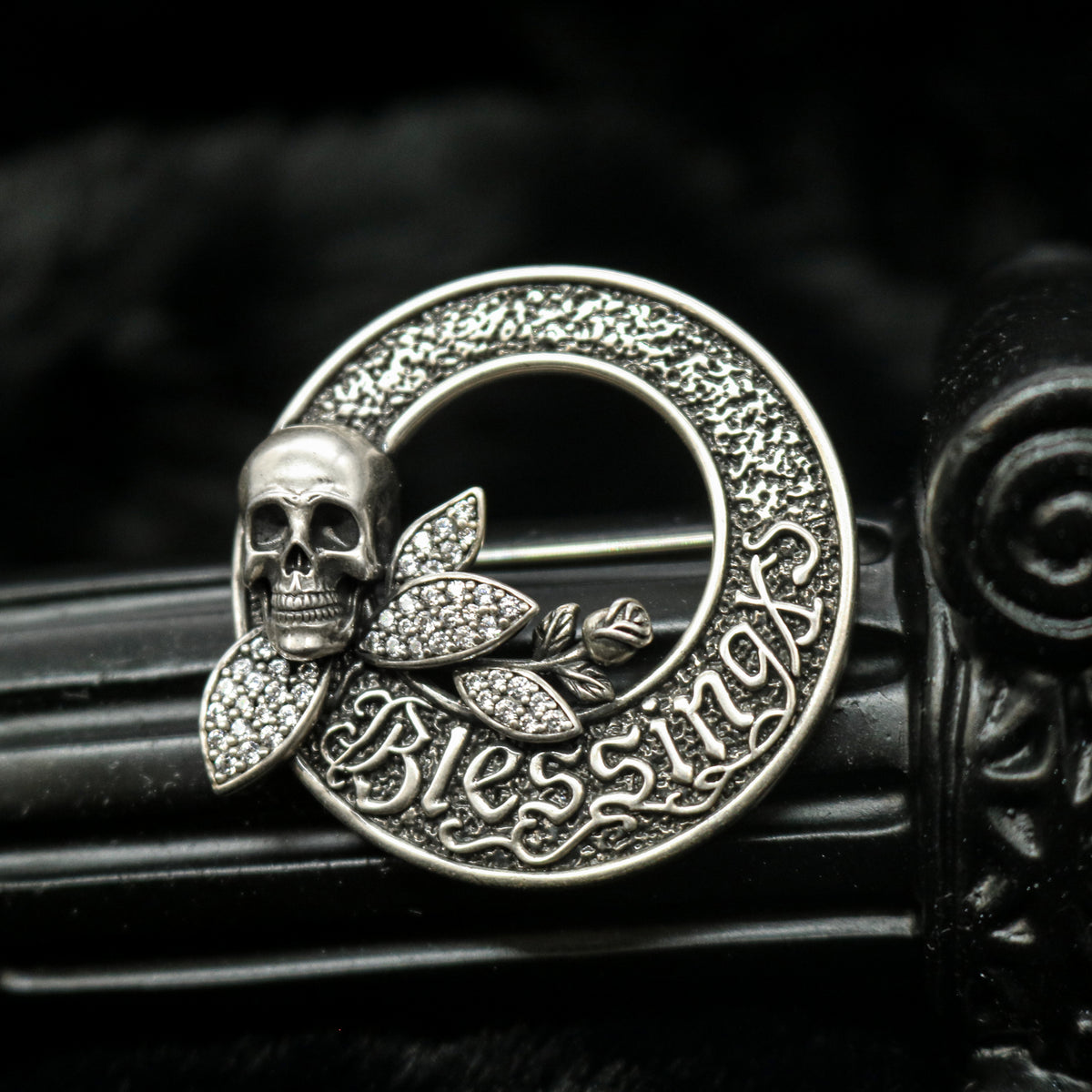 Macro view of Rock & Republic cubic zirconia skull blessing brooch in Antique Silver showing skull and crystal leaves.