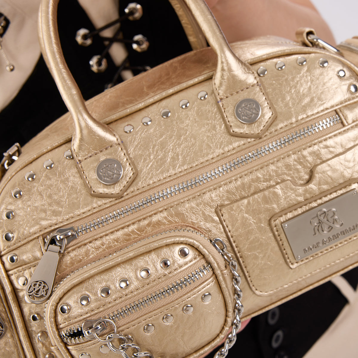 Rock & Republic Studded Mini Boston Bag in Gold PU detail view showing logo hardware, studs and compact boston shape.