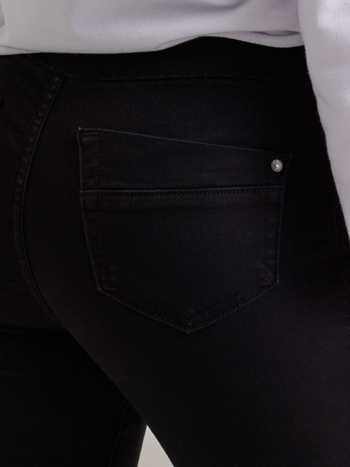 Macro view of Rock & Republic Women's Fever Legging in DNA solid black wash showing rear patch pocket and metal rivet detail.