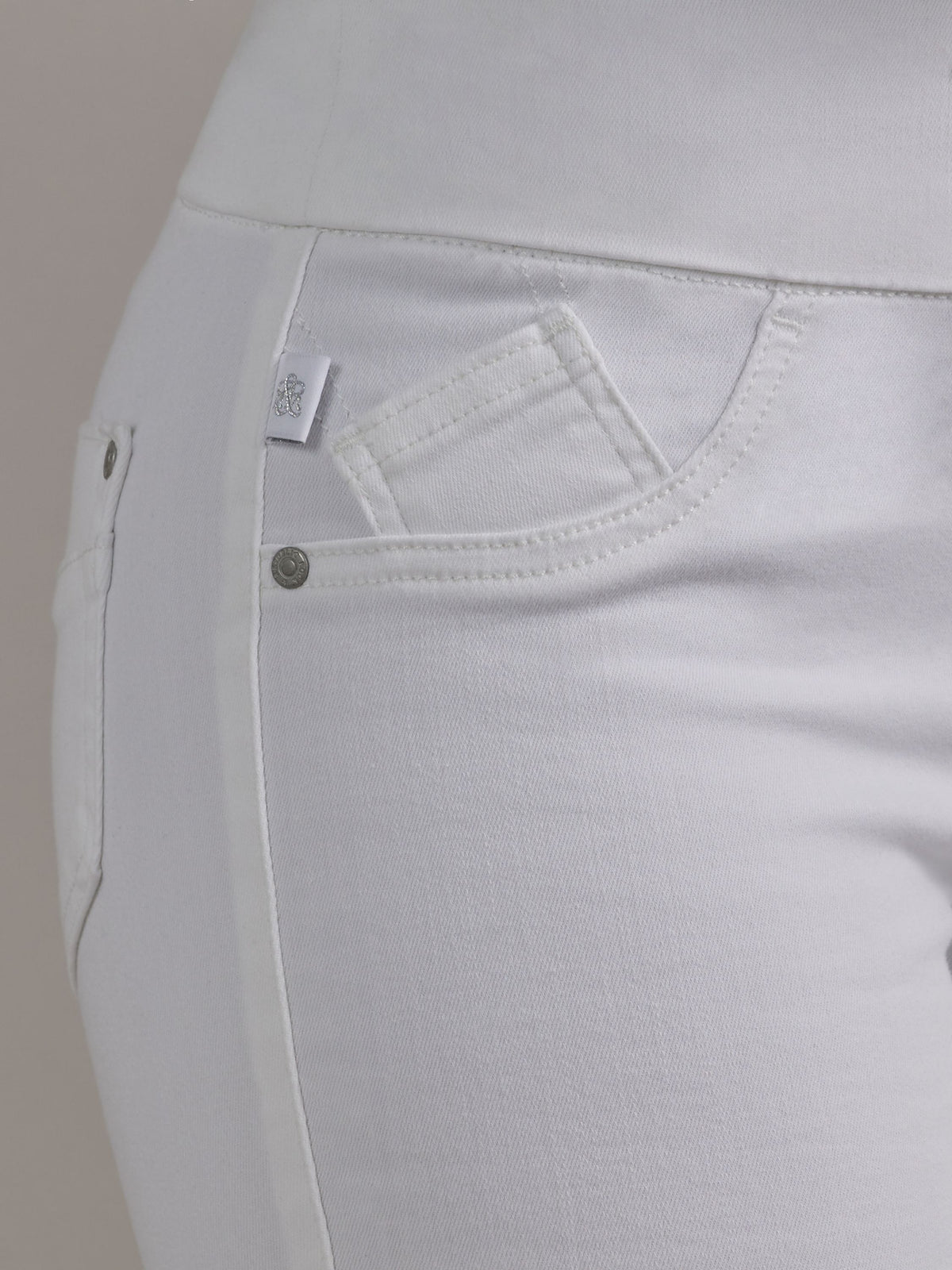 Side waist detail of Rock & Republic Women's Fever Legging in Antidote showing front pocket, rivet, and woven RR logo tab.
