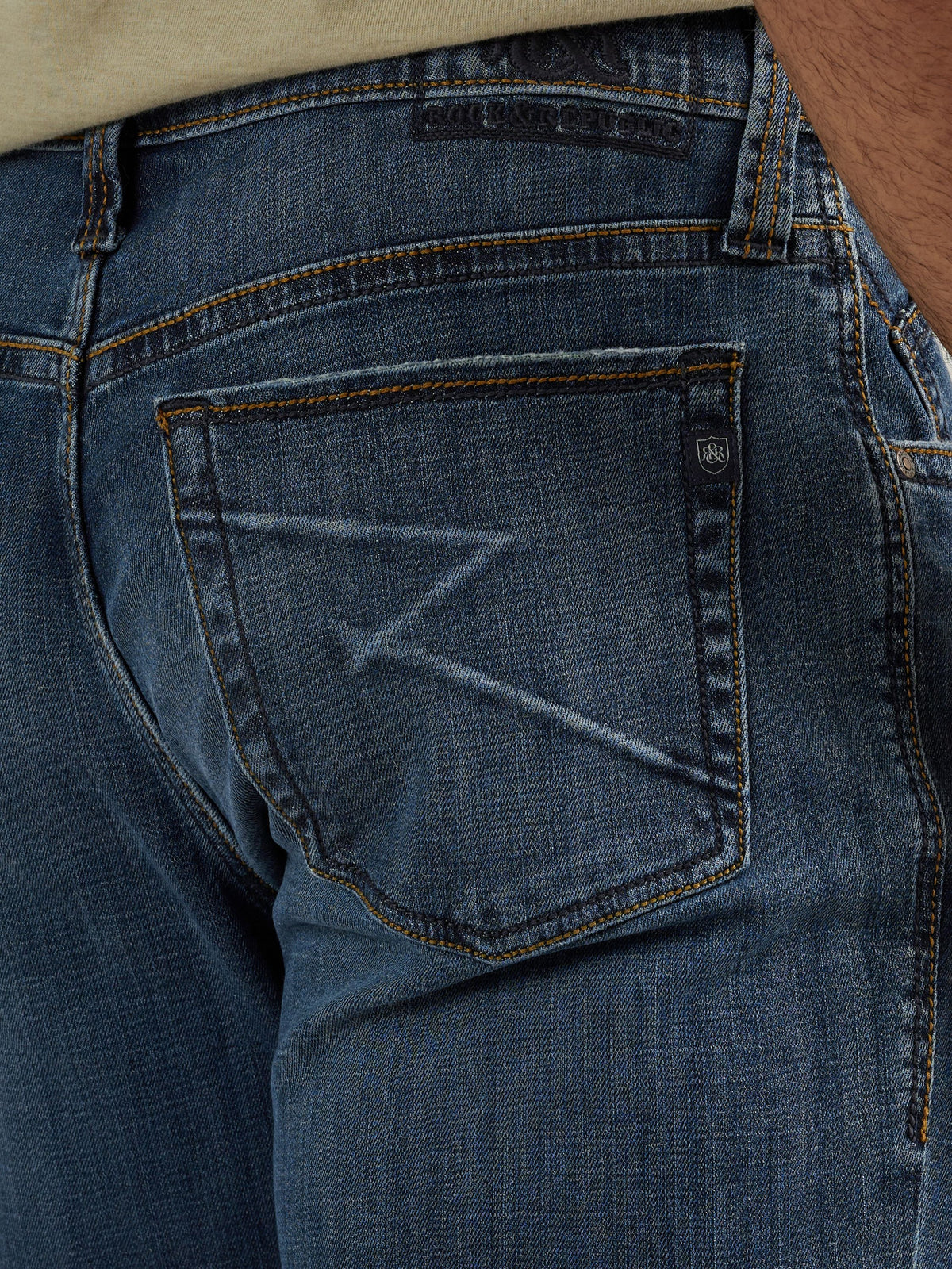 Detailed back pocket view of Rock & Republic Grady jeans in Fade Out showing geometric shadow R design and crest tab.