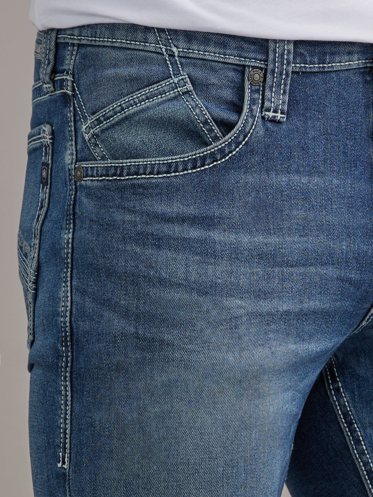 Close-up of Rock & Republic Henlee jeans front waist in Denied showing angled inset coin pocket and defined thigh fading.