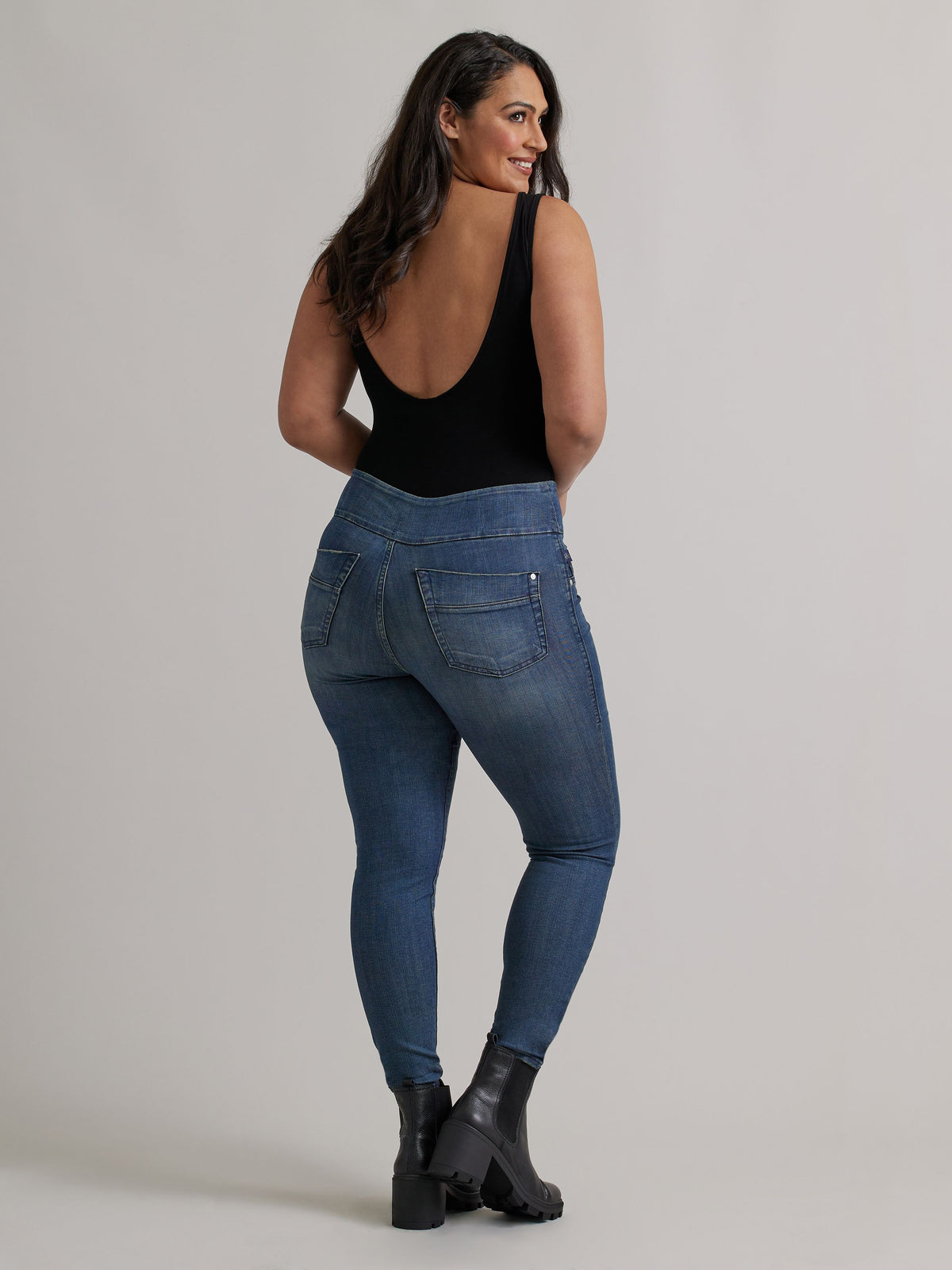 Back view of Rock & Republic Women's Fever Legging in Tried and True wash on curve model showing sculpting rear patch pockets.