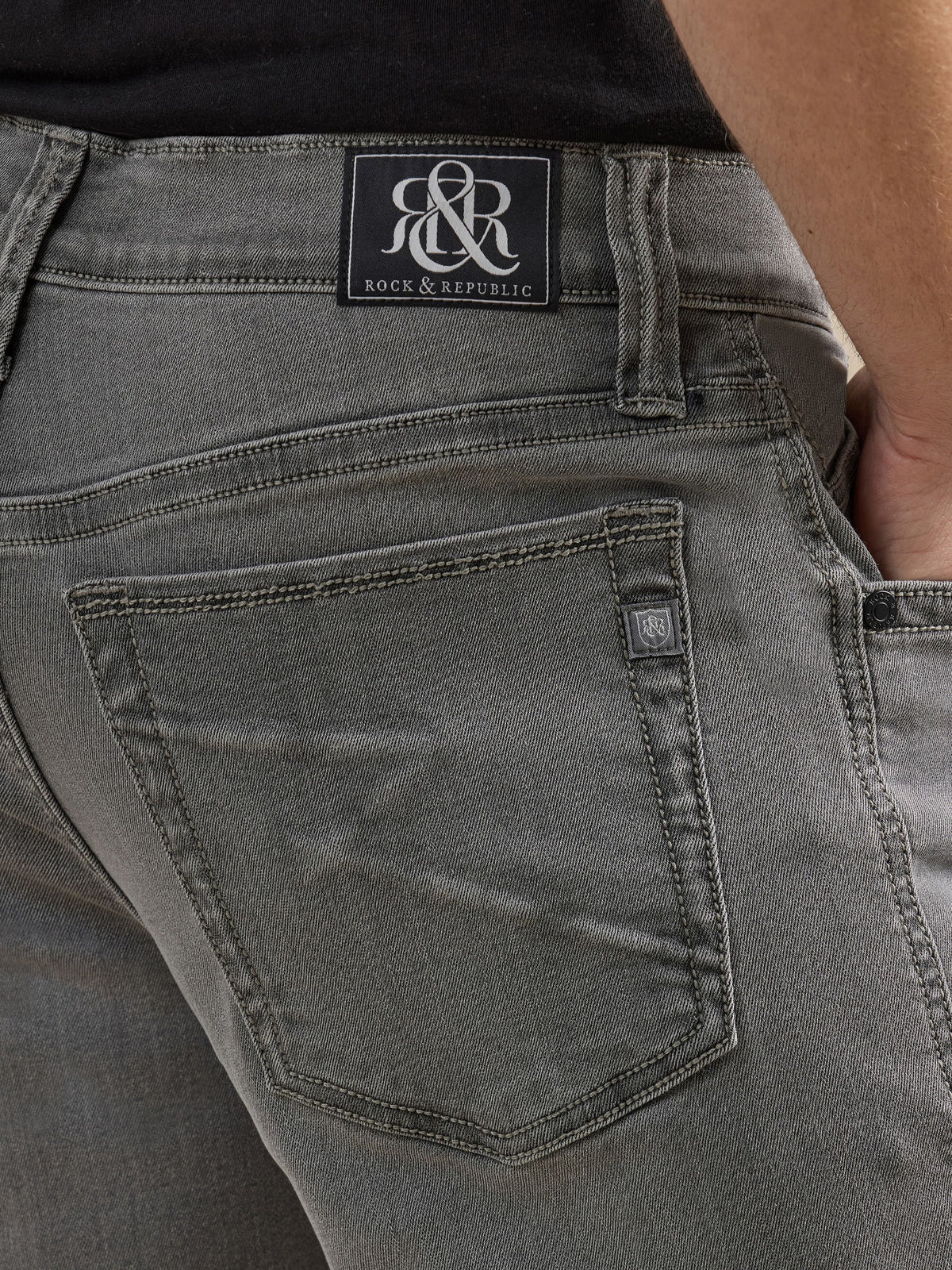 Detailed back pocket view of Rock & Republic Neil jeans in Toner Low showing black R&R waist patch and crest logo tab.
