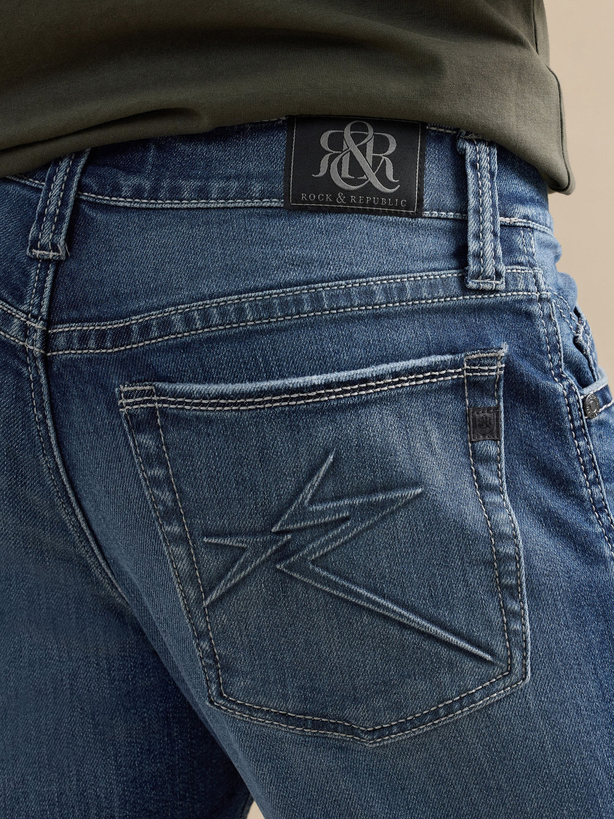 Detailed back pocket view of Rock & Republic Neil jeans in Best Bet showing star embroidery and black R&R logo waist patch.