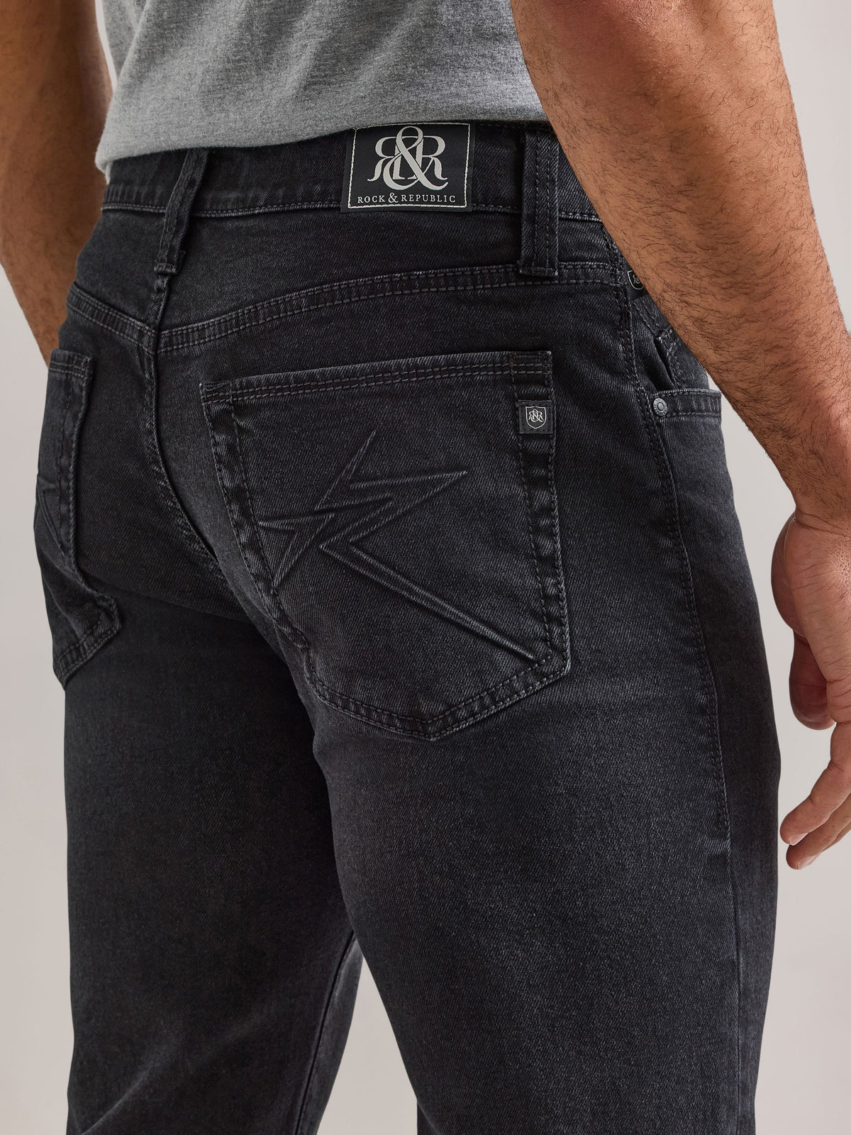 Detailed back pocket view of Rock & Republic Henlee jeans in Blackout showing tonal embroidery and crest logo tab.