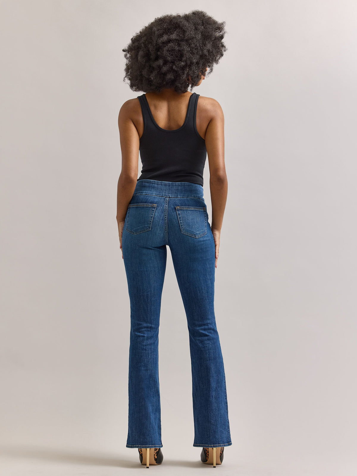 Back full view of Rock & Republic Fever pull-on bootcut jeans in Heartfelt showing clean rear pockets and flare hemline.