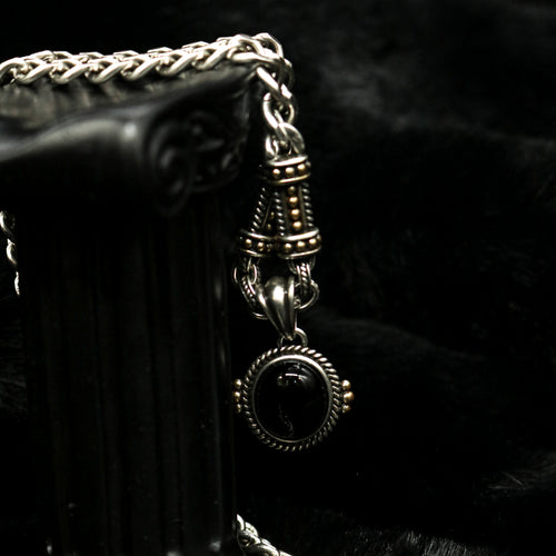 Vertical macro view of Rock & Republic black cabochon link chain necklace in Antique Silver draped on black prop column.