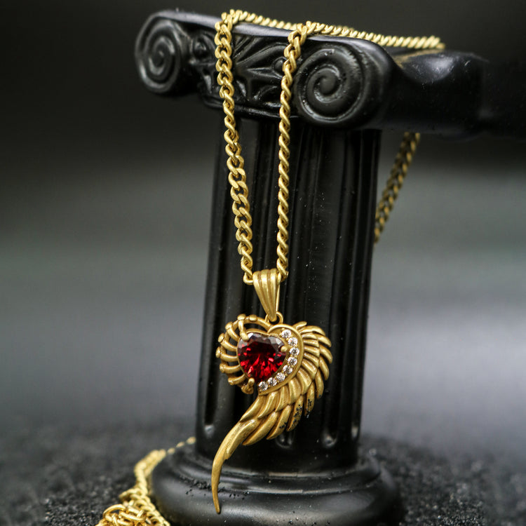Display view of Rock & Republic Crimson Spiral Wing Pendant Necklace in Gold showing red heart gem and sculpted wing.