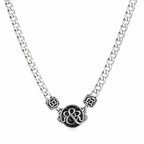 Detailed shot of Rock & Republic Crest Medallion Curb Chain Necklace in Silver showing ornate crest and cut-out beads.
