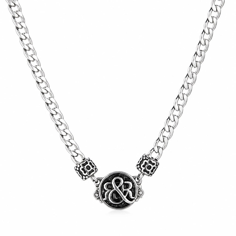 Detailed shot of Rock & Republic Crest Medallion Curb Chain Necklace in Silver showing ornate crest and cut-out beads.
