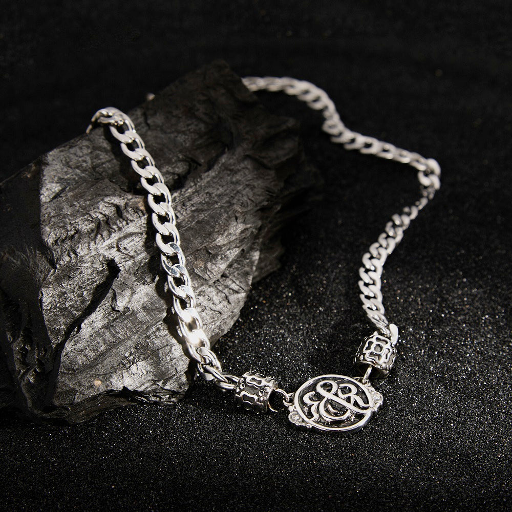 Rock & Republic Crest Medallion Curb Chain Necklace in Silver on black rock featuring weathered medallion and spacer beads.