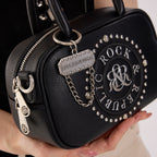 Rock & Republic Studded Logo Medallion Satchel Bag in Black PU close-up highlighting charm on satchel silhouette.