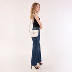 Rock & Republic Shield Lock Saddle Crossbody Bag in White PU side view on model showing vintage saddle crossbody shape.